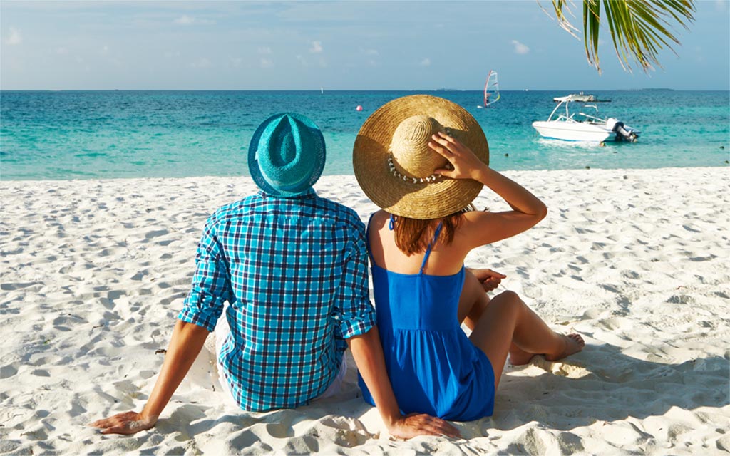 Couple sitting on the beach looking at the ocean.